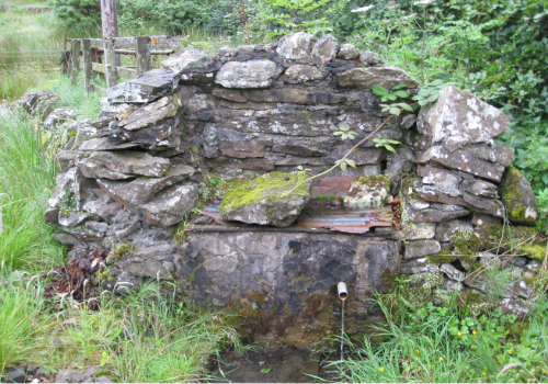St Inan's Well at the base of Lochlands Hill, Beith. Shown is a road-side cistern construction with water piped to it from the capped well further up the hill.