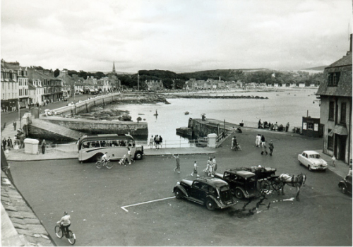 Millport Harbour in the 1950s. Note the taxis and horse carriage ready to take visitors round the island.